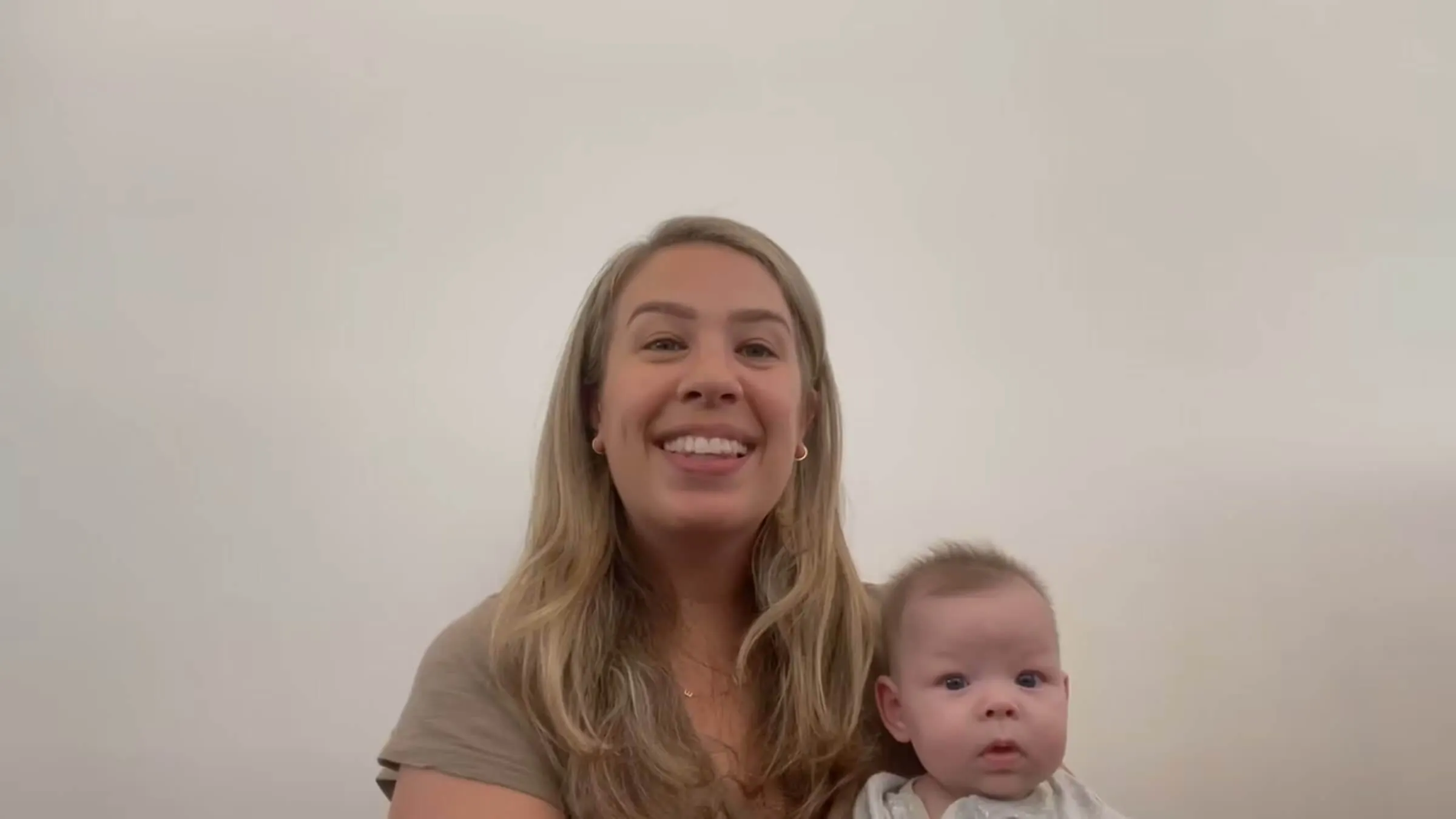 Smiling mother holding her baby, speaking to the camera