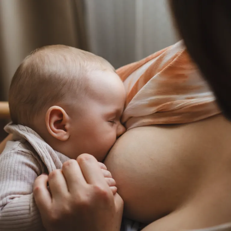Baby breastfeeding in its mother’s arms