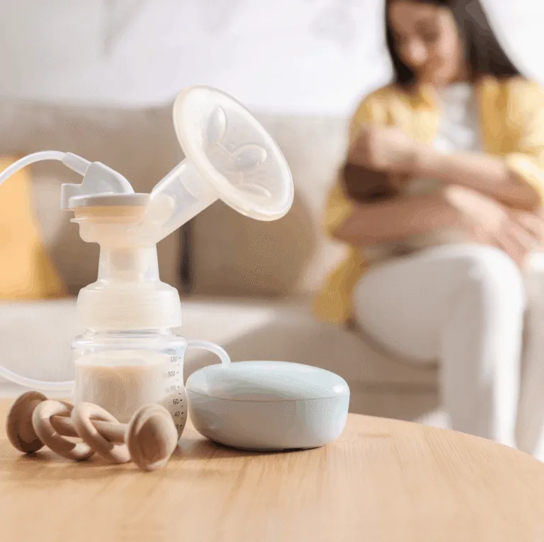 Baby bottle of breast milk beside a pump on a table