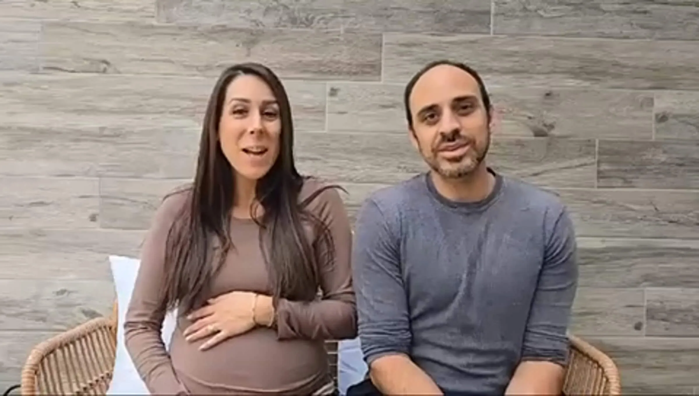 Pregnant woman and her husband sitting together, speaking to the camera