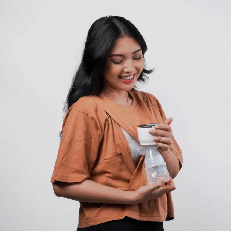 Smiling woman in an orange top using a wearable breast pump